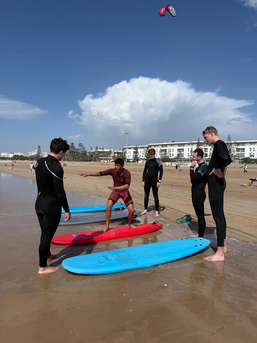 Surf lesson in Essaouira — instructor demonstrating the pop-up to the group, Windy Essaouira