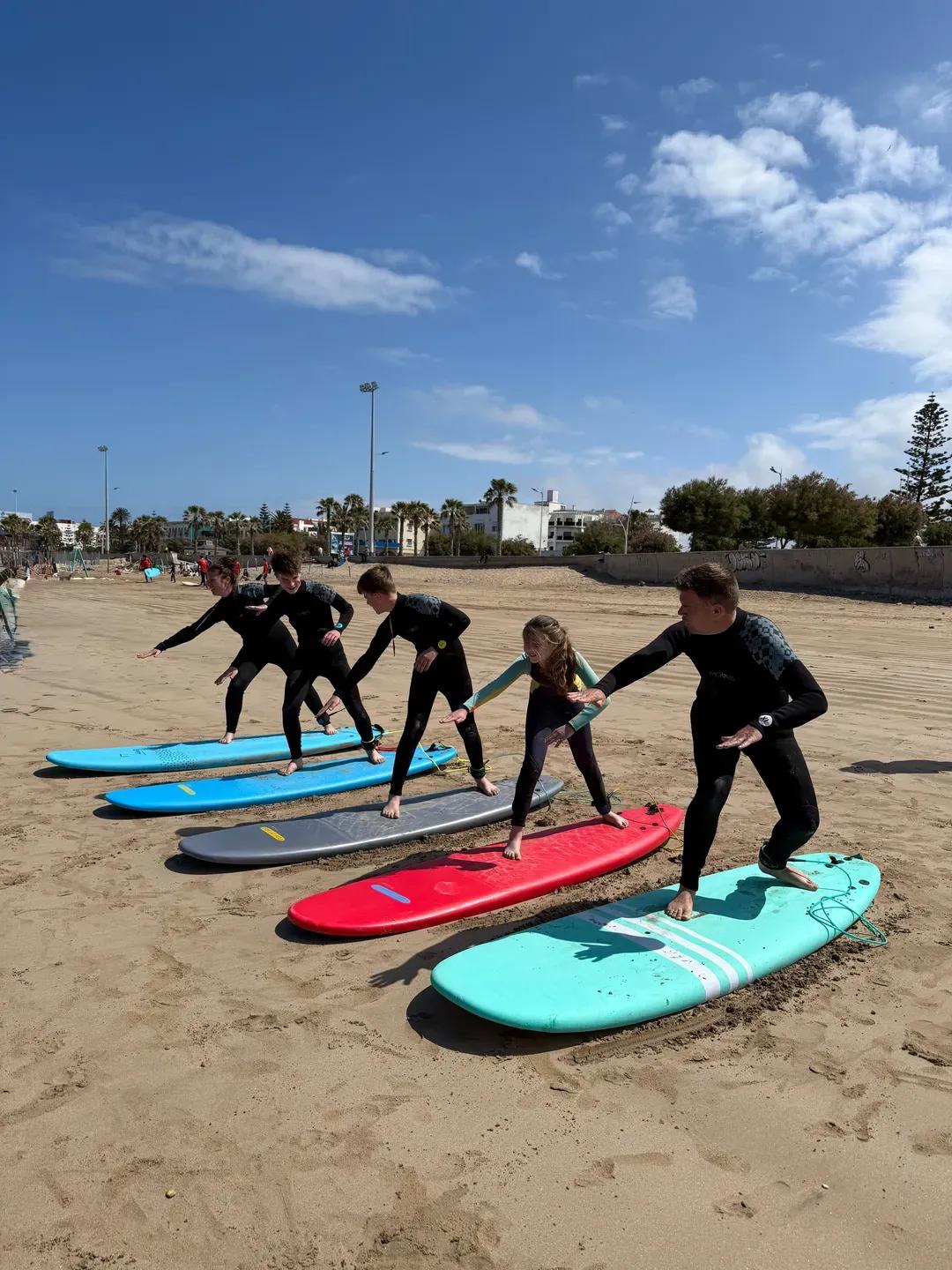 Group surf lesson in Essaouira — students learning the pop-up on the beach
