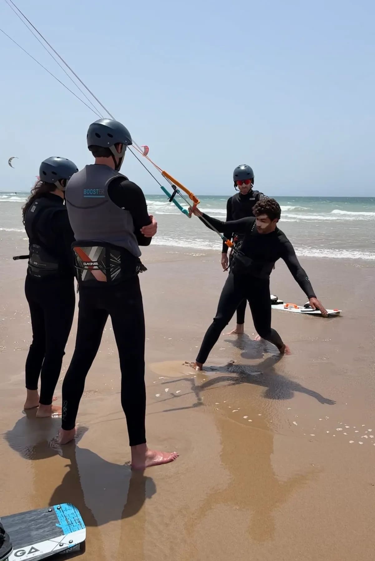 Cours de kitesurf à Essaouira — moniteur montrant la position sur la planche à deux élèves casqués sur la plage de Diabat, Windy Essaouira