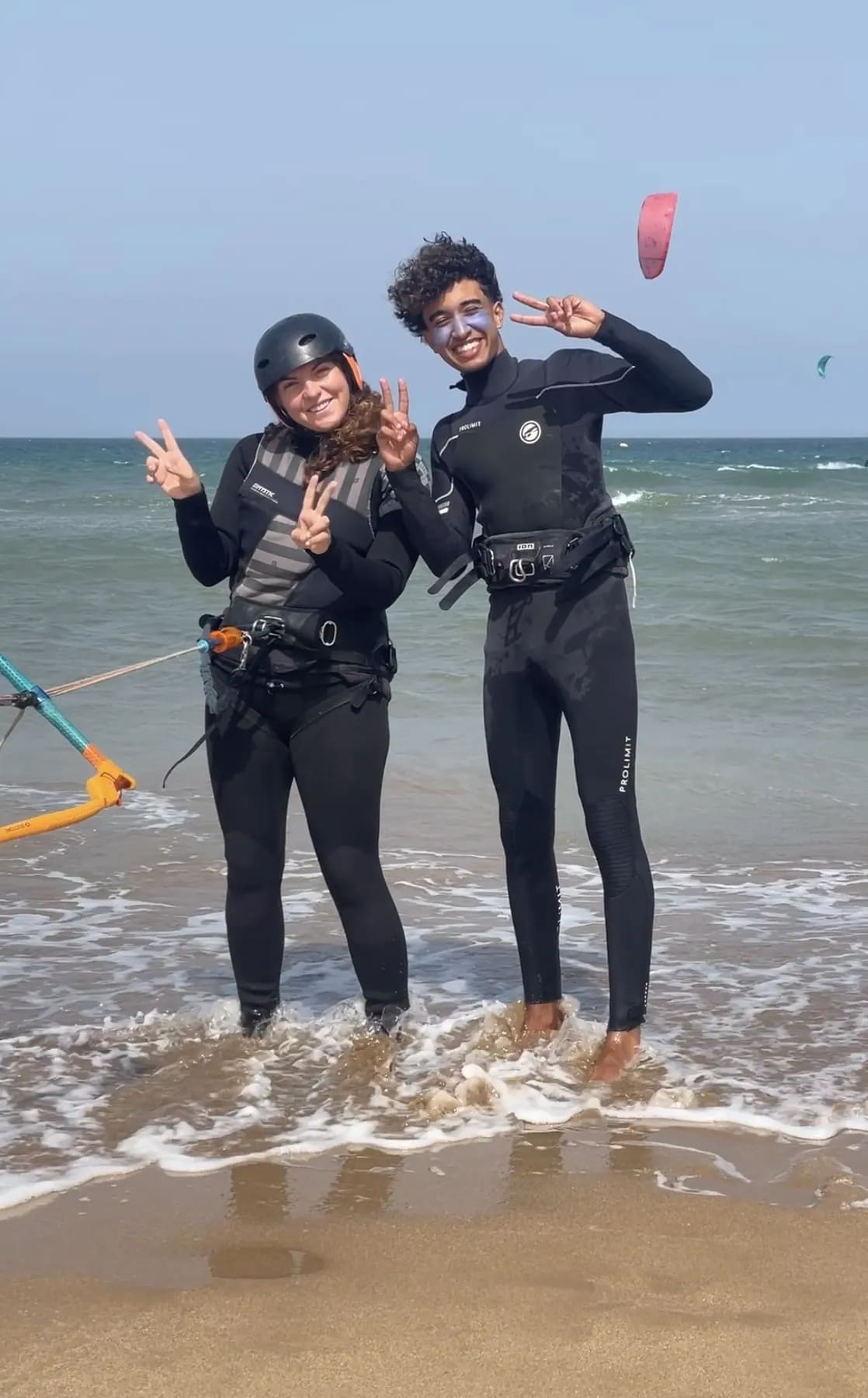 Cours de kitesurf à Essaouira — élève casquée et son moniteur IKO les pieds dans l'eau après la session, barre de pilotage à la main, Windy Essaouira