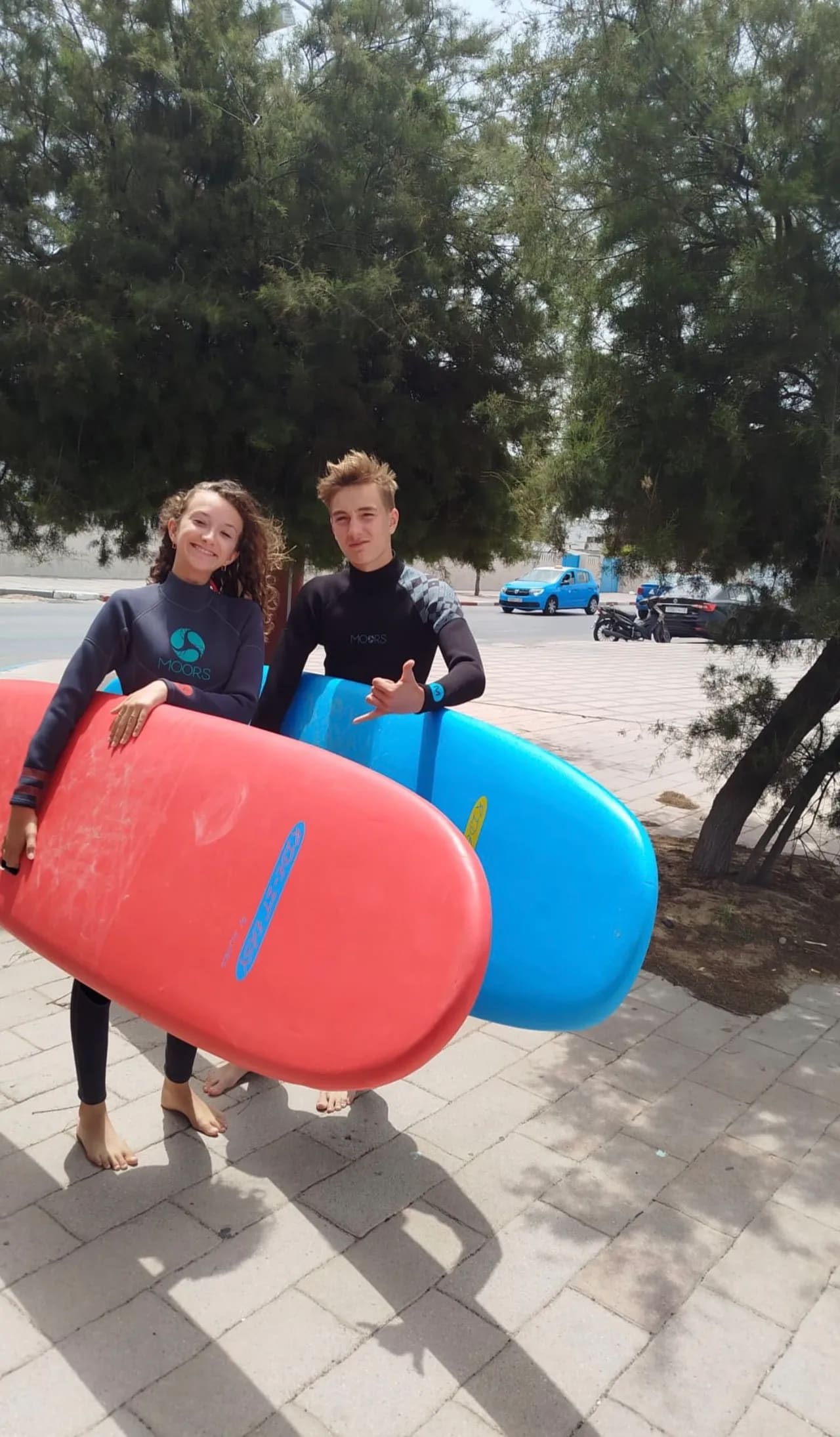 Two teenagers in wetsuits holding their foam surfboards before a kids surf lesson in Essaouira — Windy Essaouira